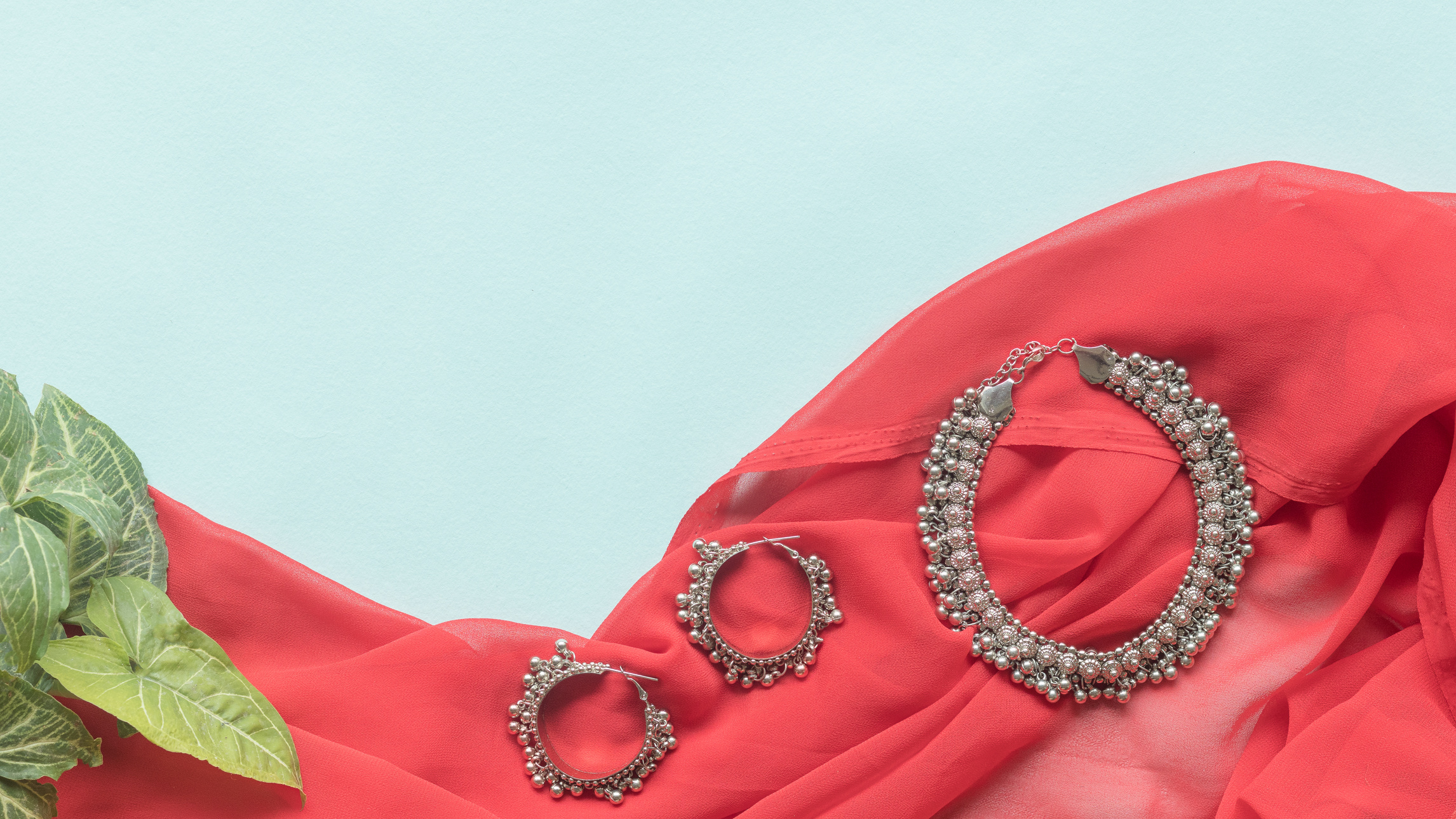 Traditional Indian Payal and Silver Earings on a Light Blue and Red background